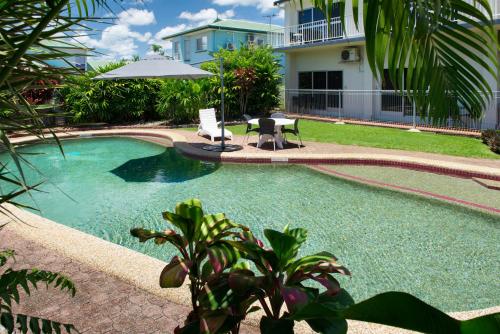 a swimming pool with a table and an umbrella at Barrier Reef Motel Innisfail in Innisfail