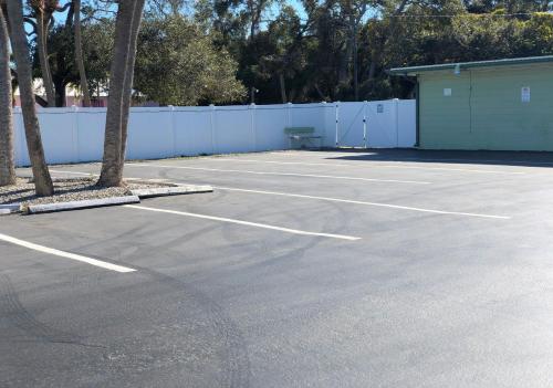 a parking lot with palm trees and a white fence at Sunshine Inn & Suites Venice, Florida in Venice