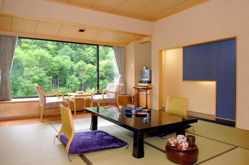 a living room with a table and chairs and a large window at Sounkyo Kankou Hotel in Kamikawa
