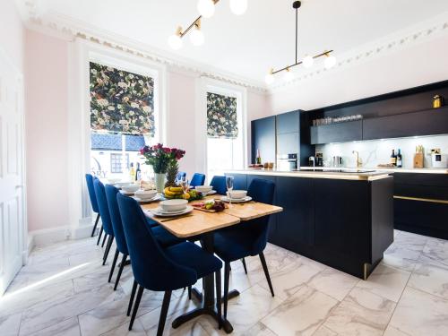 a dining room with a long table and blue chairs at Luxury Travel Emporium YO1 - Exquisite 400 Year Old, City Centre Townhouse in York