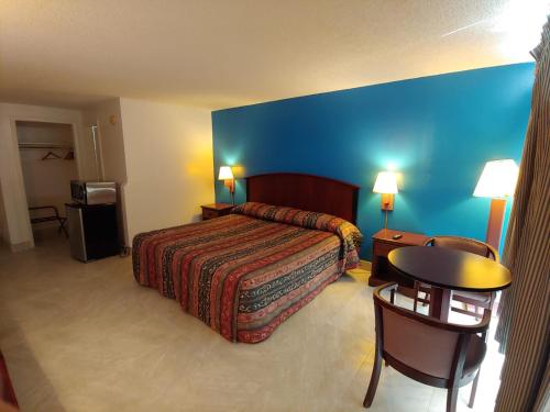 Habitación de hotel con cama y pared azul en Relax Inn Silver Springs, en Silver Springs