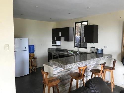 a kitchen with a counter with chairs and a refrigerator at The Heights in Montañita in Montañita