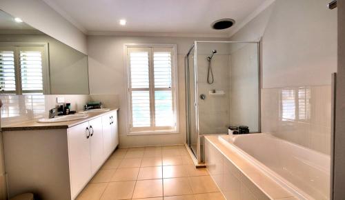a bathroom with a tub and a shower and a sink at Dragons Rest in Kingscote