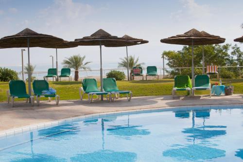 a group of chairs and umbrellas next to a swimming pool at David Dead Sea Resort & Spa in Ein Bokek