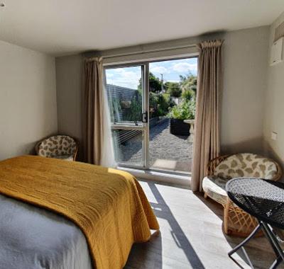 a bedroom with a bed and a large window at Garden View Cottage in Carterton