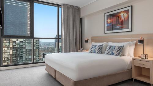 a hotel room with a large bed and large windows at Oaks Brisbane on Charlotte Suites in Brisbane