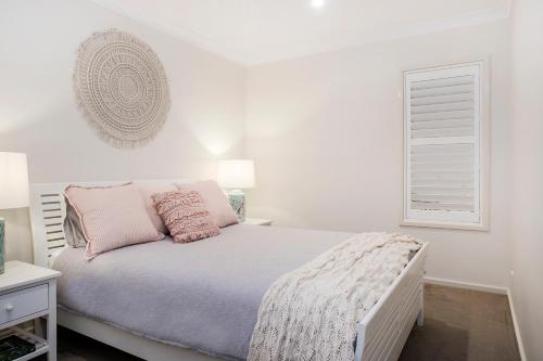Un dormitorio blanco con una cama y una ventana. en Beachfront One, Mollymook, en Mollymook