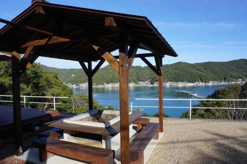 a wooden picnic table with a view of a lake at Tsubaki House in Anan