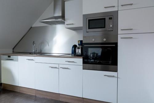 a kitchen with white cabinets and a microwave at Zimmervermietung Dietzenbach in Dietzenbach