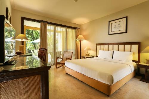 a bedroom with a bed and a desk and a television at Laras Asri Resort & Spa in Salatiga