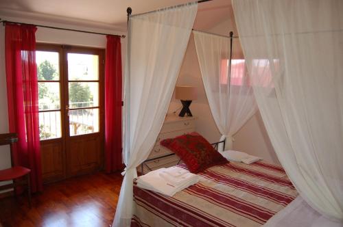 a bedroom with a canopy bed with red curtains at Villa Iriscortona in Cortona