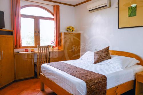 Schlafzimmer mit einem Bett und einem Fenster in der Unterkunft The Pub Hotel in Olongapo