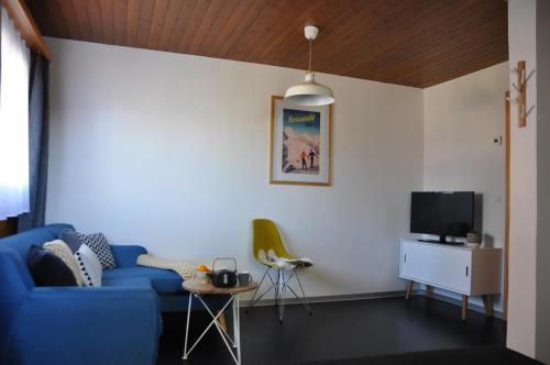 een woonkamer met een blauwe bank en een tv bij Chalet Bietschhorn Rosswald in Termen