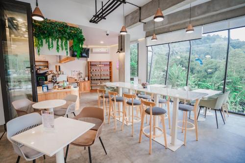 a restaurant with white tables and chairs and large windows at Passion Resort Kiriwong in Khiriwong