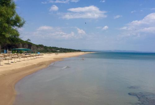 a beach with umbrellas and chairs and the ocean at Boutique Hotel Ileas Village in Arkoudi
