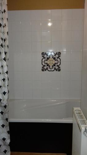 a bathroom with a white tub and a tile wall at Duplex La Maisonnette 2 Chambres - parking gratuit in Troyes