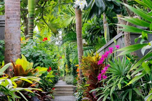 a garden with palm trees and colorful plants at Aradhana Villas by Ekosistem in Canggu