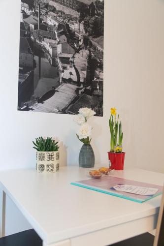 a white desk with flowers and a picture on the wall at Park City Center in Luxembourg