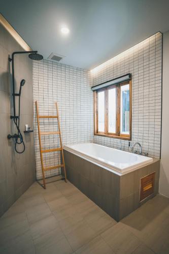 a bathroom with a bath tub and a window at Passion Resort Kiriwong in Kiriwong