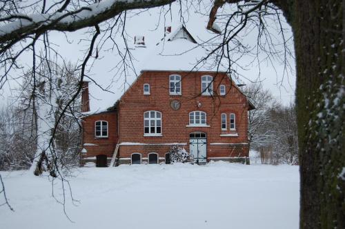a large red brick house in the snow at Ferienwohnung ehemalige Revierförsterei "Morgensünn" in Kuhstorf