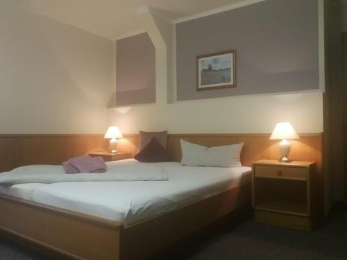 ein Schlafzimmer mit einem Bett mit zwei Lampen in der Unterkunft Hotel Waldidyll in Eggesin