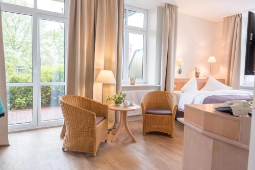 Habitación de hotel con cama, mesa y sillas en BE BIO Hotel be active en Tönning