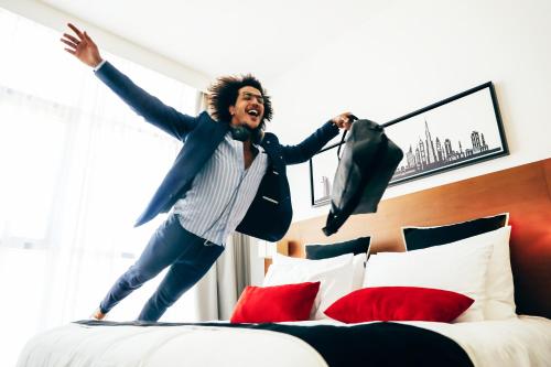 a man jumping on top of a bed at TRYP by Wyndham Dubai in Dubai