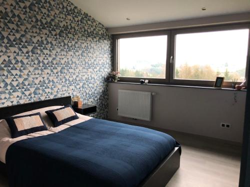 a bedroom with a blue bed and a window at By Chris in Malmedy