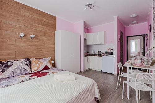 a bedroom with a bed and a table and a kitchen at Чисто и уютно как дома. Апартаменты в Одинцово in Odintsovo