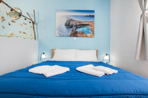 uma cama azul com duas toalhas brancas em Captain Elias Studios 2 em Cárpatos