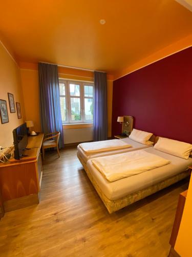 a bedroom with two beds and a television in it at Hotel da Rosario in Bad Neustadt an der Saale