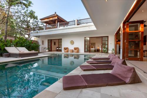 una piscina con tumbonas y una casa en Puri Temple Villa, en Canggu
