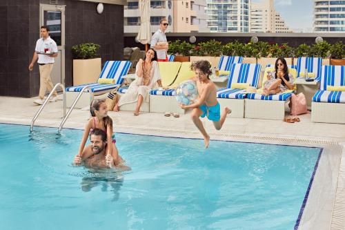 a swimming pool filled with people playing frisbee at Wyndham Dubai Marina in Dubai