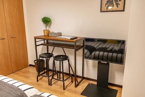 a living room with a table and a tv at Lespedeza Osaka in Osaka