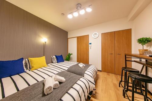 a bedroom with a large bed with blue and yellow pillows at Lespedeza Osaka in Osaka
