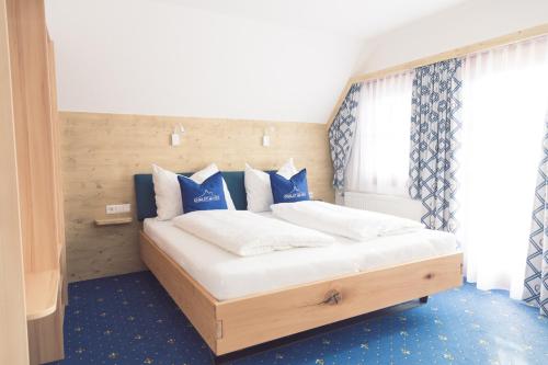 a bedroom with a bed with blue and white pillows at Chalet am See in Aich