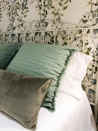 a bed with a green and white pillow on it at Casas Madre de Deus in Évora