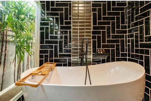 a bath tub in a bathroom with a black and white wall at The Matta in Bangkok