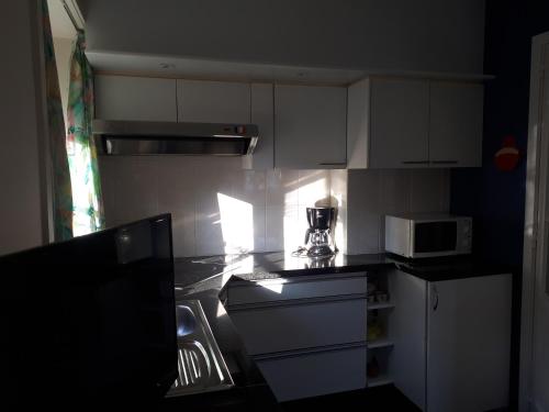 a kitchen with white cabinets and a microwave at Apartment Descamps in Blankenberge