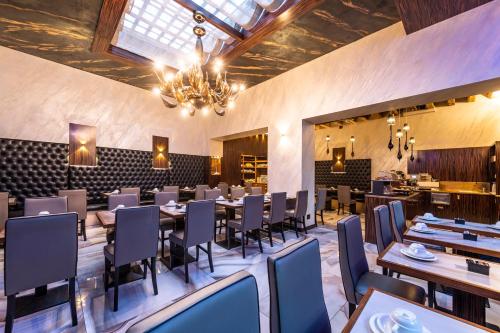uma sala de jantar com mesas e cadeiras e um lustre em Hotel Abbazia em Veneza