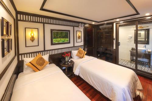 a bedroom with two beds and a table with flowers at Sena Cruises - Wonder On Lan Ha Bay in Ha Long