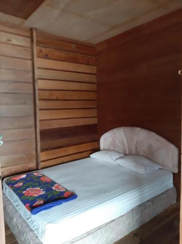 a small bed in a room with wooden walls at Beach Guest House in Maninjau