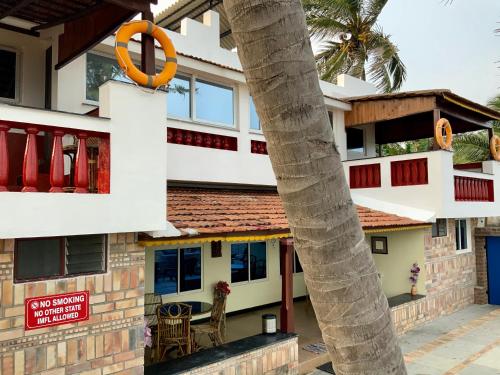 a house with a palm tree in front of it at Mermaid Island Beach Resorts in Puducherry