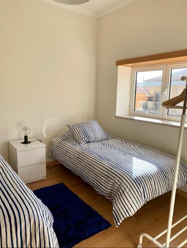 two beds in a room with a window at Beach House (Leirosa) in Figueira da Foz