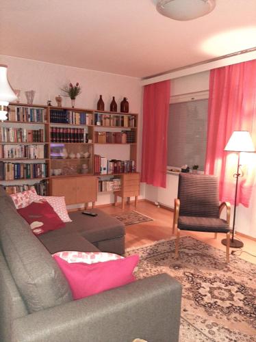 ein Wohnzimmer mit einem grauen Sofa und einem Bücherregal in der Unterkunft Apartment Vuorikatu 35 Mummola in Kuopio