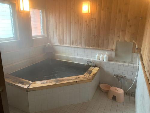Turtle Inn Nikko في نيكو: حوض استحمام كبير في حمام مع مرحاض