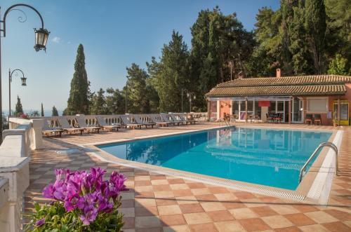 a swimming pool with chairs and purple flowers at Niki Sunrise Apartments in Gastourion
