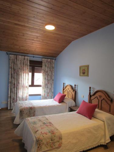 a bedroom with two beds and a wooden ceiling at Casa Rural San Isidro in Valdepiélagos