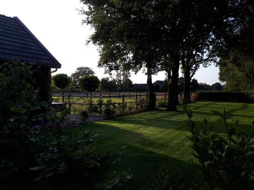 a garden with trees and a fence and grass at De Hammerhoeve in Dalfsen