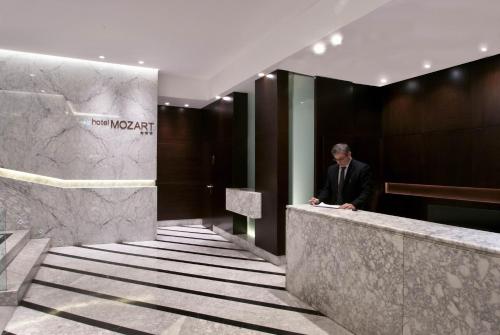 un hombre parado en un mostrador en el vestíbulo en Hotel Mozart en Valladolid